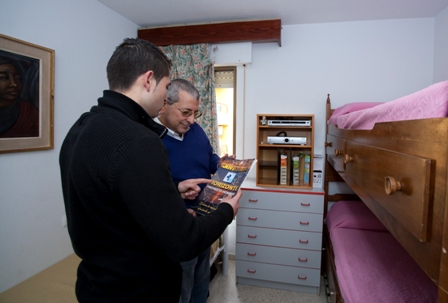 Un residente muestra una revista a un voluntario en una de las habitaciones